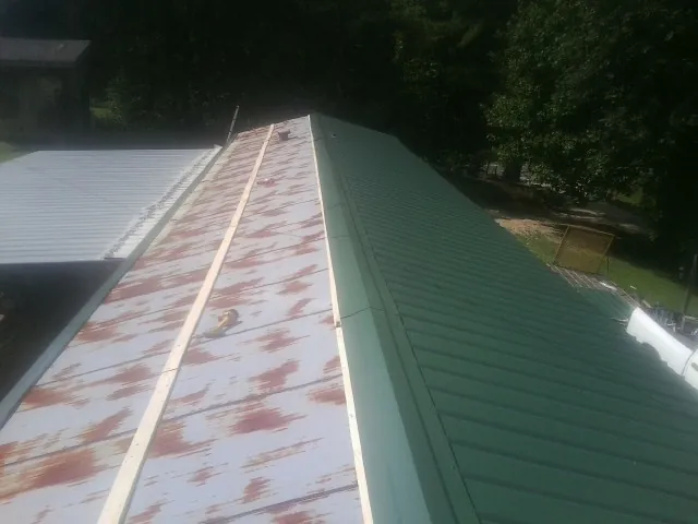 Old rusted panels beside newly installed green metal roofing — Wind Damage Roof Repair by Roofing Brothers in Varnville