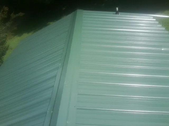 New green metal panels meeting at the ridge of a roof — Flat Roof Repair work by our crew in Varnville