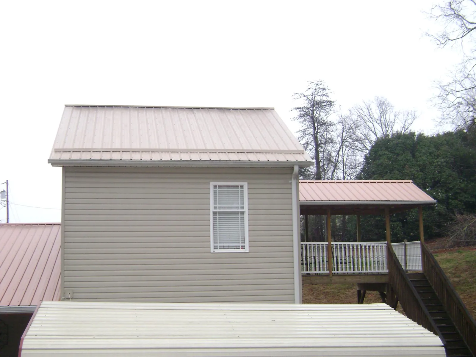 Tan metal roofs on a two story addition and attached porch, from a Roof Replacement job in Varnville