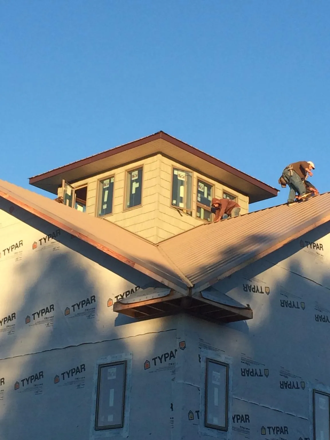 Roofers working around a rooftop cupola on a new metal roof at sunset — Roof Waterproofing in Varnville by Roofing Brothers